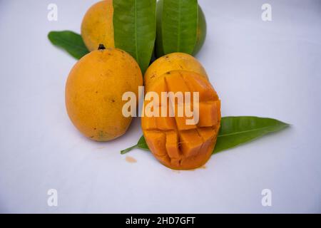 Frische köstliche Slice Gelb reifen Mango mit grünem Blatt auf isoliertem Hintergrund Stockfoto