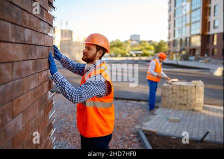 Arbeiter Verkleidung Stein für externe Wand Erwärmung Stockfoto