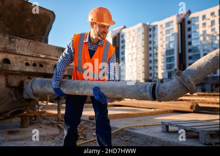 Männlicher Bauarbeiter, der das Verbindungsrohr am Standort anführt Stockfoto