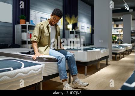 Mann, der sich für eine Matratze entscheidet, sitzt auf einem Lader Stockfoto
