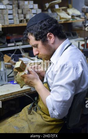 Ein Rabbiner & Meister stellt in einer heimischen Werkstatt Tefillin-Boxen aus Leder her. In Brooklyn, New York City. Stockfoto