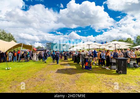 Schlammiges Gras und Leute, die sich beim Eastival Food and Music Festival 2021, Three Mills Island, London, Großbritannien, treffen Stockfoto