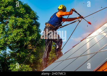 Arbeiter waschen Photovoltaikpaneele auf dem Dach mit Druckwasser Stockfoto