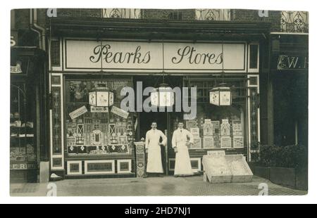 Original-Postkarte aus Edwardian mit Pearks Läden, Supermarkt, Ladengeschäft, 2 Ladenbesitzer stehen draußen. Edwardianisches Geschäft / viktorianisches Geschäft. Das Geschäft verkauft Peark's Butter, berühmte Huntley and Palmers Biscuits, frische Eier, Obst, hausgemachtes Hackfleisch zur Weihnachtszeit, ca. 1910, Großbritannien Stockfoto