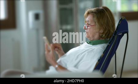 Ältere Frau, die das Telefon benutzt, ältere Person, die das Smartphone am Touchscreen hält Stockfoto