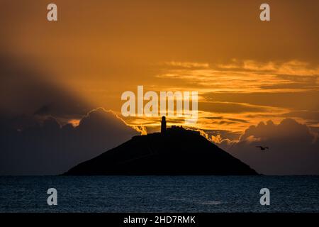 Ballycotton, Cork, Irland. 04th. Januar 2022. Sonnenschein bricht bei Sonnenaufgang hinter Ballycotton Island in Co. Cork, Irland, durch Wolken. - Bild David Creedon Stockfoto