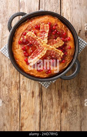 Aggakaka Egg Cake ist ein traditionelles skandinavisches Gericht, das mit gebratenen Schweinebauch- und Preiselbeeren in der Pfanne auf dem Holztisch serviert wird. Vert Stockfoto