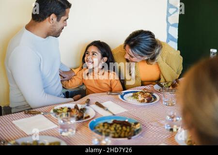Lateinamerikanische Eltern haben Spaß mit ihrer Tochter während des Abendessen zu Hause - Fokus auf Mädchen Gesicht Stockfoto