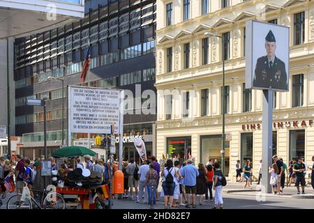 Menschenmenge am Checkpoint Charlie im Sommer. Ehemaliger Grenzübergang zwischen West-Berlin und Ost-Berlin während des Kalten Krieges. Gebäude im Hintergrund Stockfoto