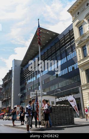 Menschenmenge am Wachposten der US-Armee am Checkpoint Charlie. Ehemaliger Grenzübergang zwischen West- und Ost-Berlin kalter Krieg. Wolken blauer Himmel Hintergrund. Stockfoto