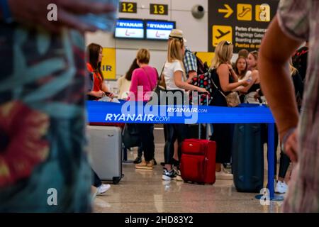 Palma, Spanien - 25. September 2019: Passagiere mit Gepäck warten in der Flughafenhalle auf Check-in-Schalter, Details zum blauen Grenztrenner mit Ryanai Stockfoto