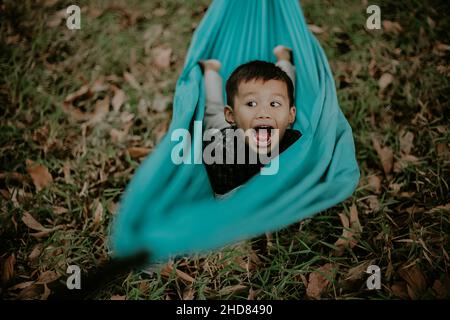 Ausdruck eines Jungen, der auf einer Schaukel spielt Stockfoto