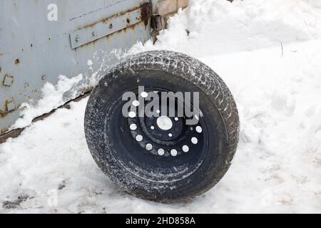 Das Rad für das Auto steht in der Nähe auf dem Schnee Stockfoto