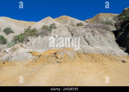 Steile, blaue Tonhänge, mit abfallenden Trümmern, die auf Kalkstein entlang der Küste von Gozo, Malta, Geröll bilden Stockfoto