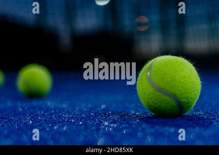 Selektiver Fokus. Zwei Paddle-Tennisbälle auf einem blauen Paddle-Tennisplatz in der Nacht. Schlägersportkonzept. Stockfoto