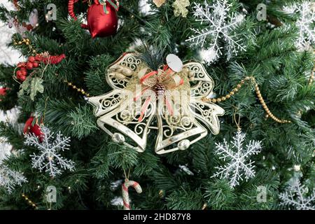 Nahaufnahme einer goldenen Glocke, die an einem geschmückten Weihnachtsbaum mit Kopierraum hängt. Weihnachten und Neujahr Urlaub Hintergrund. Stockfoto