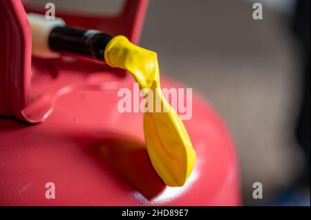 Selektiver Fokus auf den Rand eines aufblasbaren Ballons, der an einem Heliumbehälter befestigt ist. Stockfoto