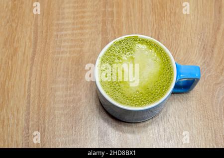 Blauer Becher mit grünem, schaumigen Matcha-Tee Stockfoto