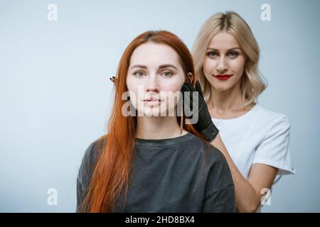 Master Kosmetikerin macht Markup von Augenbrauen Tätowierung, Frauen vor der Anwendung von Permanent Make-up, dauerhafte Augen Make-up und Augenbrauen Korrektur Verfahren. Happy Client Mädchen ist sehr zufrieden Stockfoto