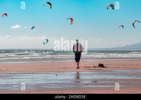 Mann, der am Strand in Fonte da Telha läuft. Menschen Kitesurfen. Stockfoto