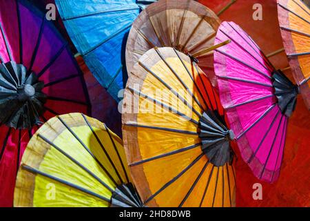 Farbenfrohe, traditionelle Papierschirme, die in einem Stall auf dem Nachtmarkt in der Fußgängerzone im Zentrum von Luang Prabang, im Norden von Laos, Südostasien, ausgestellt sind Stockfoto