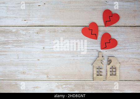 Scheidung, Teilung des Eigentums, Armut und kein Geld Konzept. Holzhaus mit gebrochenem Herzen und Haus auf Holzhintergrund. Hypothek, Miete, immobilienmakler Stockfoto