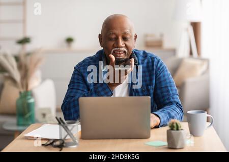 Älterer Afrikaner Mit Sprachsuche Auf Dem Smartphone Im Büro Stockfoto