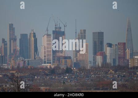 London, Großbritannien. 4. Januar 2022. Sinkende Temperaturen und strahlender Himmel über dem Zentrum Londons, wenn die untergehende Sonne die hohen Bürohochhäuser der City of London trifft, von Wimbledon aus gesehen über Vorstadthäusern im Vordergrund. Quelle: Malcolm Park/Alamy Live News Stockfoto