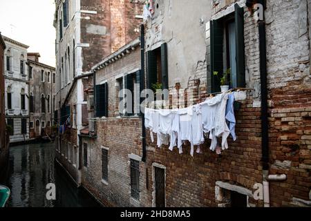 Die Wäsche hängt an der Wand eines Hauses in einem kleinen Wasserweg in Venedig. Stockfoto