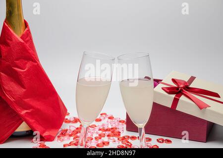 Zwei Gläser Champagner und ein Geschenk auf weißem Hintergrund mit Kopierfläche. valentinstag, Muttertag, Hochzeit. Stockfoto