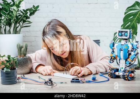 Ein Teenager-Mädchen, das Kabel an Sensorchips ansteckt, während er arduino-Codierung und Robotik lernt Stockfoto