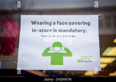 Slough, berkshire, Großbritannien. 30th. Dezember 2021. Ein Gesichtsmaskenschild in einem Schaufenster. Quelle: Maureen McLean/Alamy Stockfoto