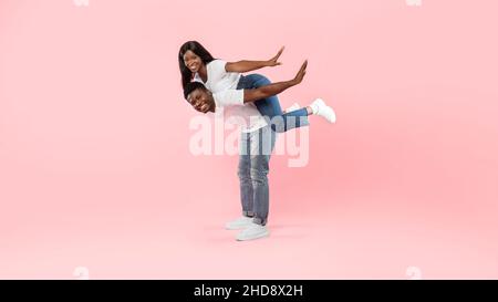 Afroamerikanischer Mann, der auf dem Rücken eine Frau reitet Stockfoto
