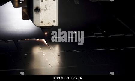 Blech in der Werkstatt schneiden. Clip. Faserlasermaschinen für das Schneiden von Metall in Nahaufnahme. Modernes Werkzeug in der Schwerindustrie. Gefährliche Arbeit. Hochpräzise Fertigung Stockfoto