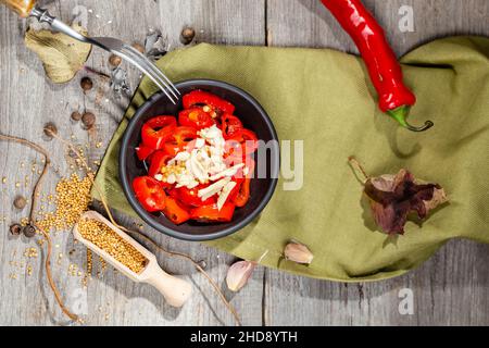 Gehackte und eingelegte Red Hot Chili Pepper Canning Vorspeise mit Knoblauch und Senf in einer schwarzen Schüssel auf dem rustikalen Holztisch serviert Stockfoto