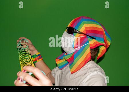 Vaduz, Liechtenstein, 24. Dezember 2021 eine Person mit einer Regenbogenfahne um den Kopf spielt mit einem Slinky Stockfoto