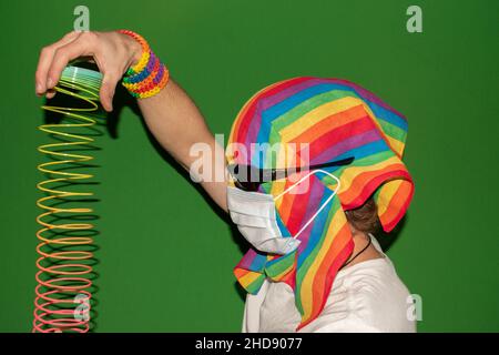 Vaduz, Liechtenstein, 24. Dezember 2021 eine Person mit einer Regenbogenfahne um den Kopf spielt mit einem Slinky Stockfoto