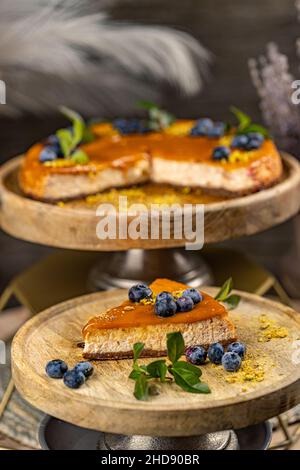 Scheibe leckerer Käsekuchen mit gesalzener Karamellsauce auf der Oberseite, verziert mit Heidelbeere Stockfoto