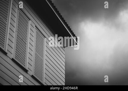 Graustufen-Aufnahme der Hauswand gegen den Himmel. Stockfoto