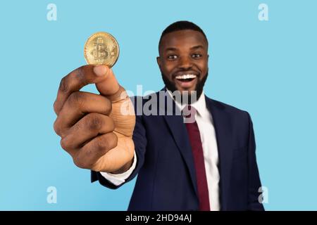 Mining Von Kryptowährungen. Porträt Eines Glücklichen Schwarzen Geschäftsmannes In Suit Holding Golden Bitcoin Stockfoto