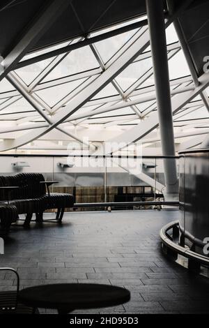 Vertikale Aufnahme des Bahnhofs Kings Cross mit Stühlen und Glasdach, London, Graustufenbild Stockfoto