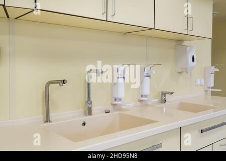 Ellenbogen Seife und antiseptischen Spender oder Desinfektionsmittel Wand zur Händedesinfektion und Wasserhahn Waschbecken mit Wasserhahn Bad oder Klinik montiert Stockfoto