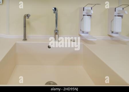 Ellenbogen Seife und antiseptischen Spender oder Desinfektionsmittel Wand zur Händedesinfektion und Wasserhahn Waschbecken mit Wasserhahn Bad oder Klinik montiert Stockfoto