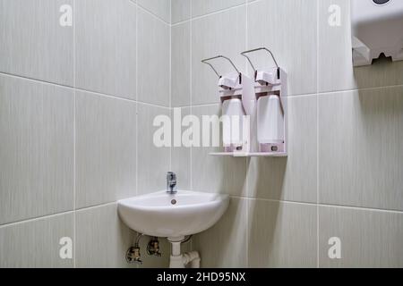 Ellenbogen Seife und antiseptischen Spender oder Desinfektionsmittel Wand zur Händedesinfektion und Wasserhahn Waschbecken mit Wasserhahn Bad oder Klinik montiert Stockfoto