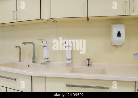 Ellenbogen Seife und antiseptischen Spender oder Desinfektionsmittel Wand zur Händedesinfektion und Wasserhahn Waschbecken mit Wasserhahn Bad oder Klinik montiert Stockfoto