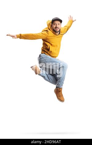 Junger Mann in einem gelben Sweatshirt springt und lächelt isoliert auf weißem Hintergrund Stockfoto
