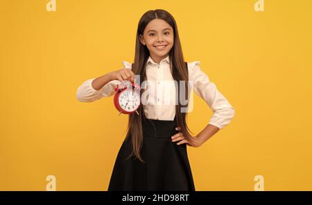 Letzte Chance. Pünktliche Teenager-Mädchen Überprüfung der Zeit. Fröhliches Kind mit Wecker. Stockfoto