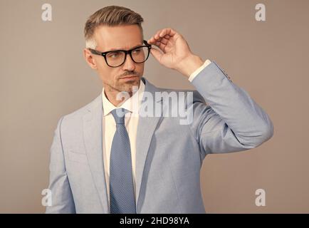 Erfolgreicher Mann in Geschäftsanzug und Brille auf grauem Hintergrund, Erfolg Stockfoto