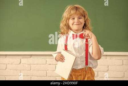 Lächelndes Kind mit Buch. Jugendlicher Junge im Klassenzimmer. Zurück zur Schule. Wissenstag. Stockfoto
