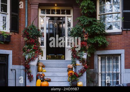 Blick auf einen Eingang zum Apartmentgebäude. Stoop mit Pflanzen, Blumen und Kürbissen für Thanksgiving Holiday Stockfoto